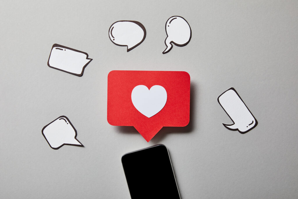 smartphone with paper like sign, thought and speech bubbles on white surface
